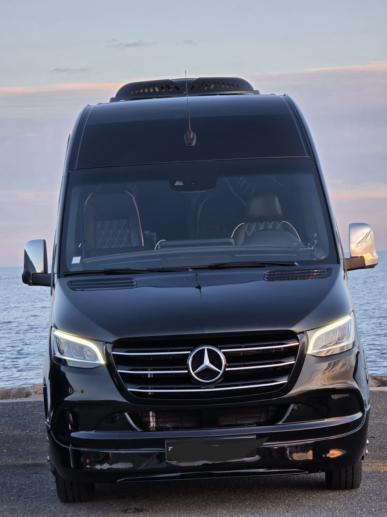 Front view of the black Mercedes Sprinter VIP chauffeur minibus at sunset on the French Riviera